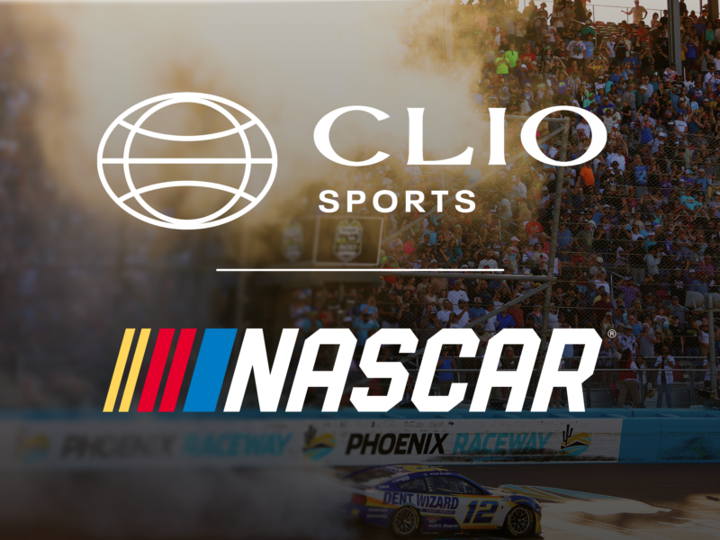 NASCAR branding over a crowded race stadium with smoke and a racing car on the track at Phoenix Raceway